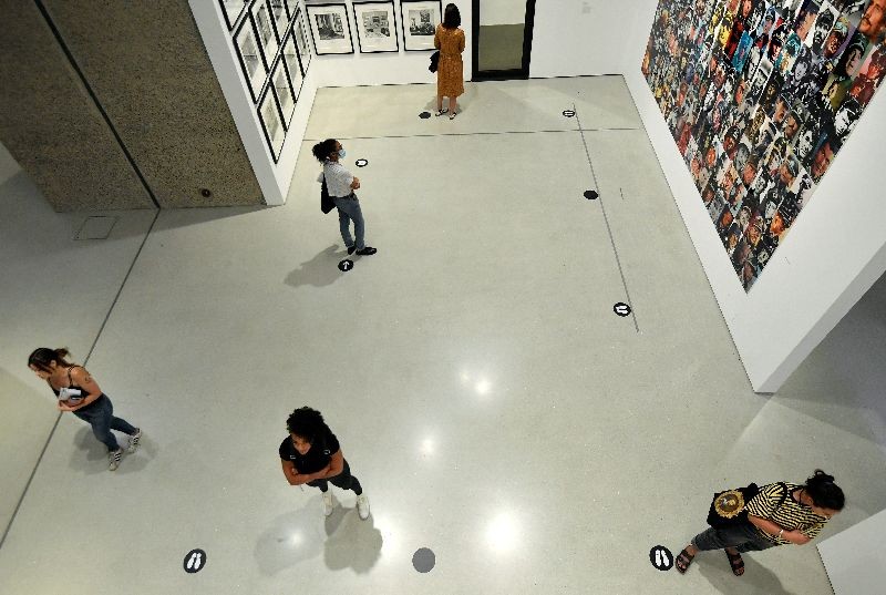 Visitors stand next to social distancing markers as they view photographs in the exhibition 'Masculinities' at the Barbican arts centre, on the first day of its reopening following the easing of lockdown restrictions after the spread of the coronavirus disease (COVID-19), in London, Britain, July 13, 2020. REUTERS/Toby Melville